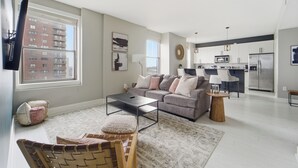En moderne stue med sofa, sofabord og et spiseområde med stole.