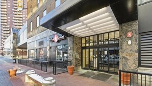 En sushirestaurant med en moderne facade, udendørs siddepladser og en væg med stenkledelse.