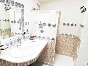 A bathroom with a white sink, a mirror, and a shower area. - Locanda Jannas (Orgosolo)