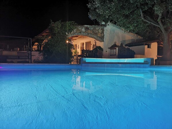 A swimming pool with a stone wall and a tree in the background. - Locanda Jannas (Orgosolo)