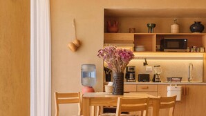 Een moderne keuken met houten kastjes, een eettafel met stoelen, een hanglamp en een vaas met bloemen.