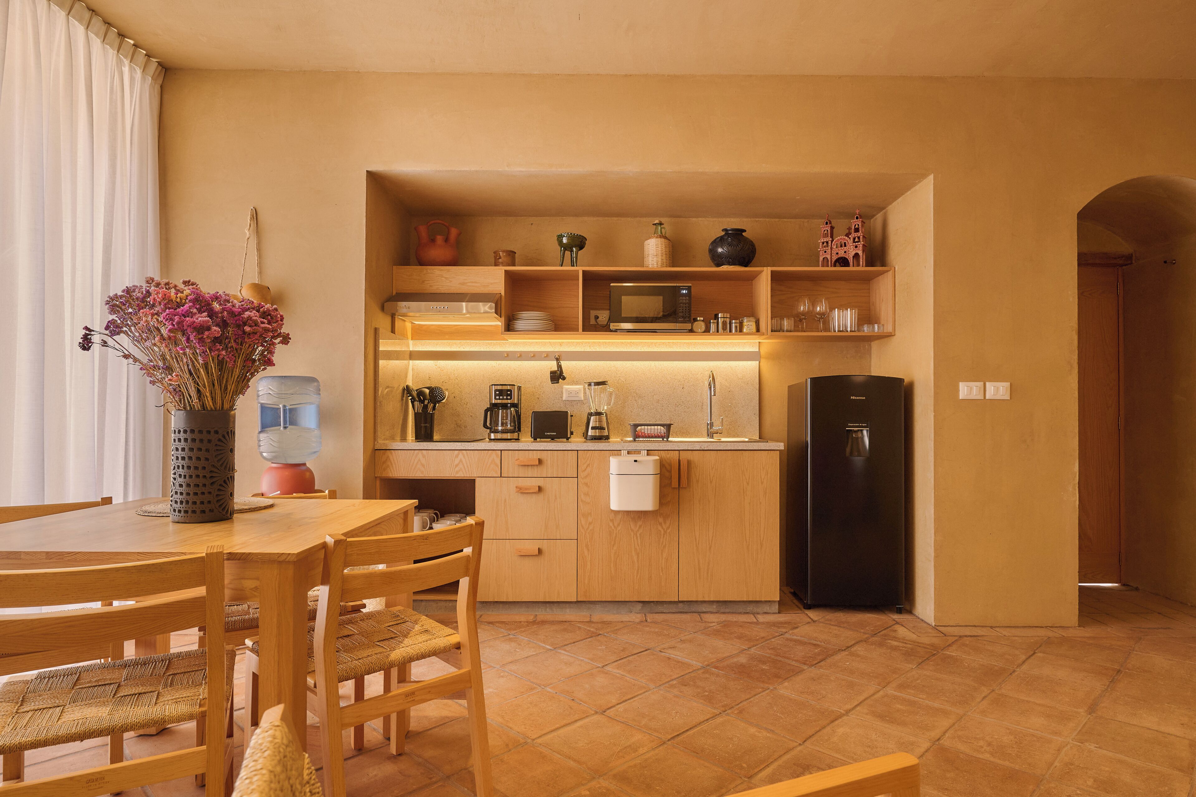 Een kleine keuken met houten kastjes, een magnetron en een koelkast.