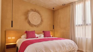 Een slaapkamer met een groot bed, een nachtkastje, decoratieve wandcirkel en een raam met gordijnen.