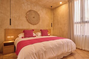 A bedroom with a large bed, a nightstand, a wall-mounted decorative piece, and a window with curtains. - Casona Xochimilco - Xochimilco (Oaxaca de Juárez)