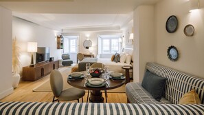 Ein modernes Wohnzimmer mit Essbereich, einer Couch und einem Fernseher.