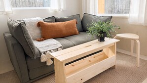 A modern living room with a grey sofa, a wooden coffee table, and a small round table.