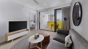 A modern living room with a flat-screen TV, a sofa, a coffee table, and a ceiling fan.