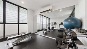 A modern gym with exercise equipment, large windows, and a mirror.