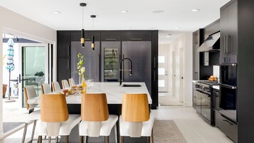 Una cocina moderna con armarios oscuros, una isla central con asientos y un horno empotrado.