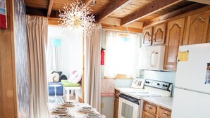 A kitchen with wooden cabinets, a white countertop, a stove, and a refrigerator. - Pet-Friendly Coastal Cottage • Walk to Pier (Old Orchard Beach)