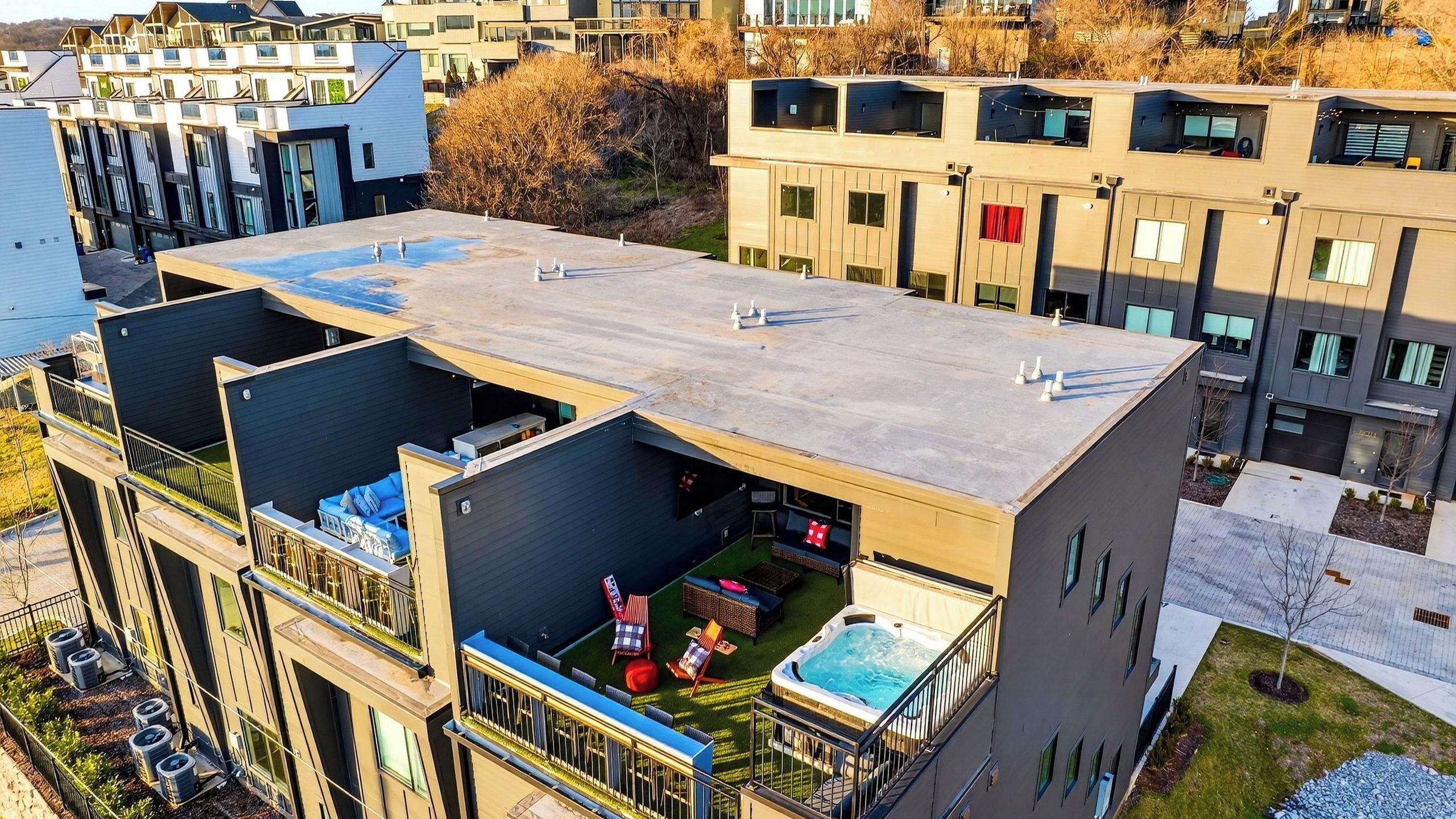 A modern multi-story building with balconies, a rooftop terrace, and a hot tub.