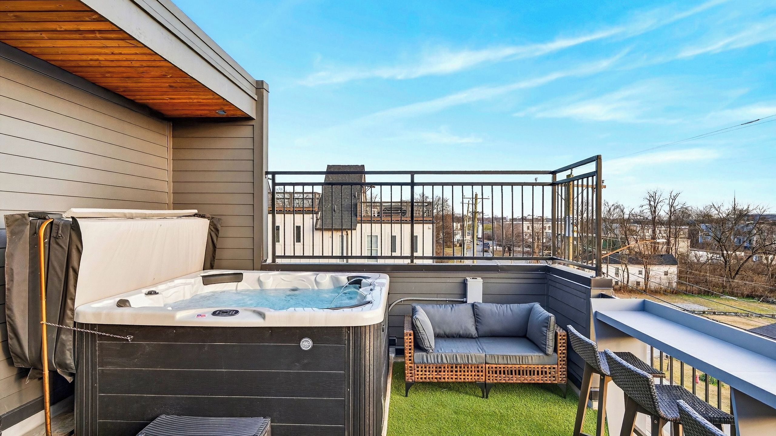 A balcony with a hot tub, outdoor seating, and a view of the neighborhood.