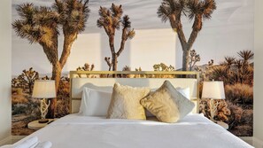 A bed with white linens, two bedside lamps, and a desert-themed mural on the wall. - The Lodge by Avantstay Private Rooftop Lounge + Hot Tub + Skyline Views + Near Broadway (Nashville)
