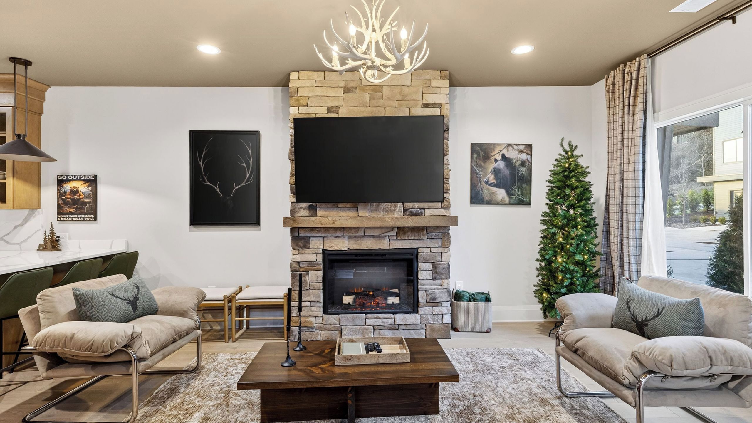 A modern living room with a stone fireplace, a flat-screen TV, and a Christmas tree.