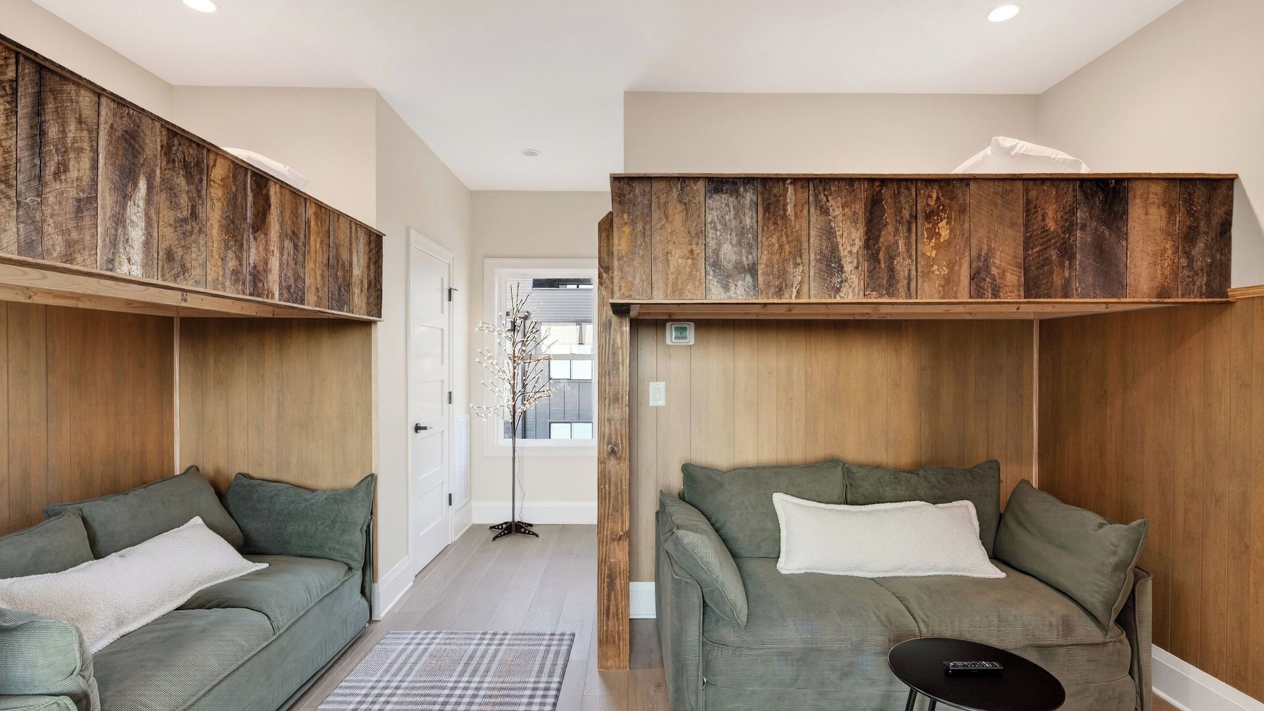 A room with two green sofas, a small black table, and a wooden ceiling.