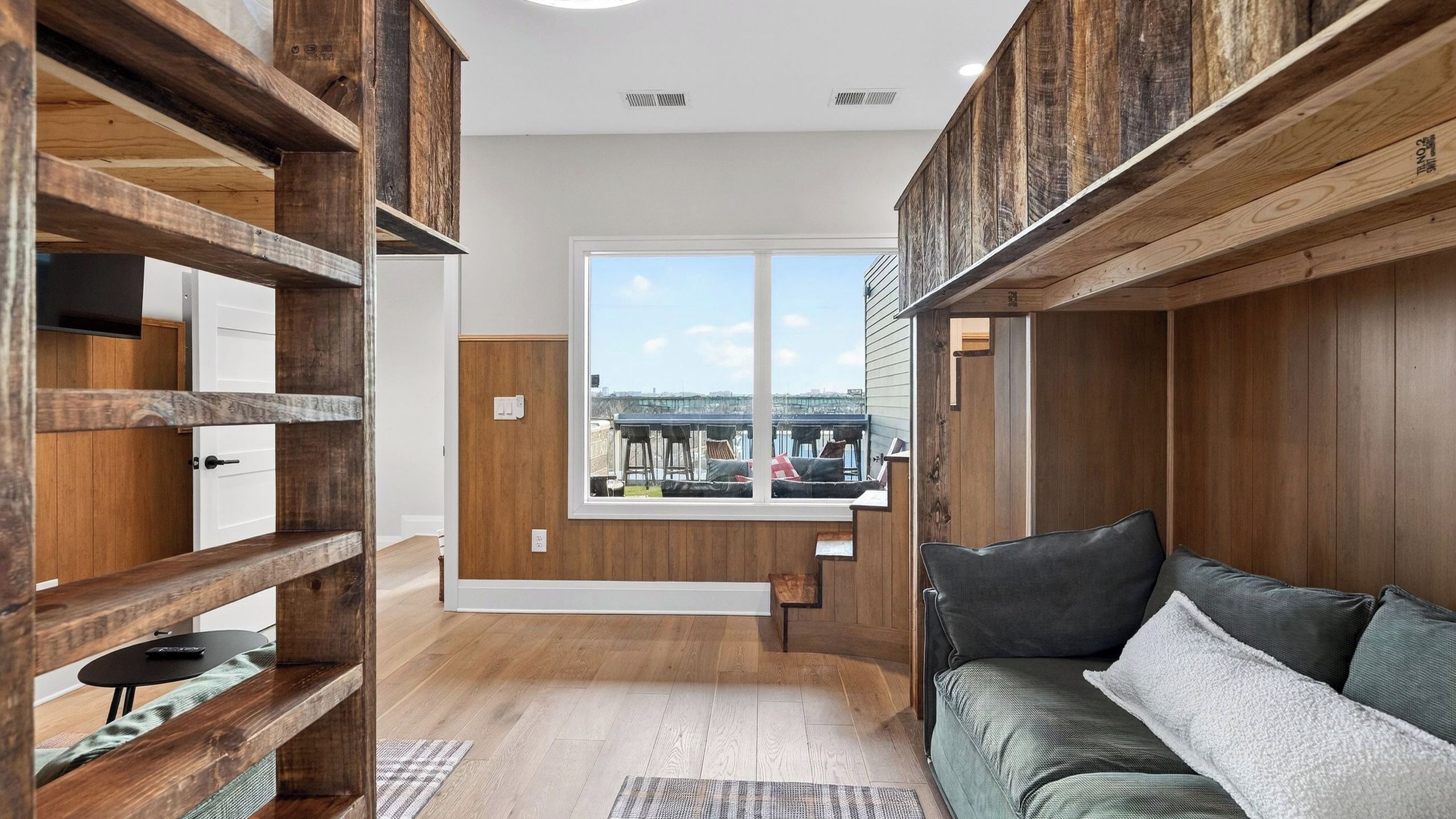 Una habitación con vigas de madera, un sofá, una ventana con vistas y una puerta.