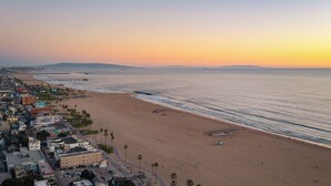 A coastal cityscape with a wide beach, a pier, and buildings along the shore. - Venice Veranda by Avantstay 3-min Walk to Beach + Rare Walk Street EV Charger + Firepit + Outdoor Dining (Venice)