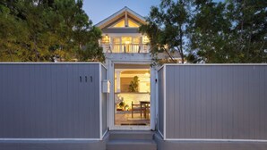 A two-story house with a balcony, a gated entrance, and a visible patio area with outdoor furniture. - Venice Veranda by Avantstay 3-min Walk to Beach + Rare Walk Street EV Charger + Firepit + Outdoor Dining (Venice)