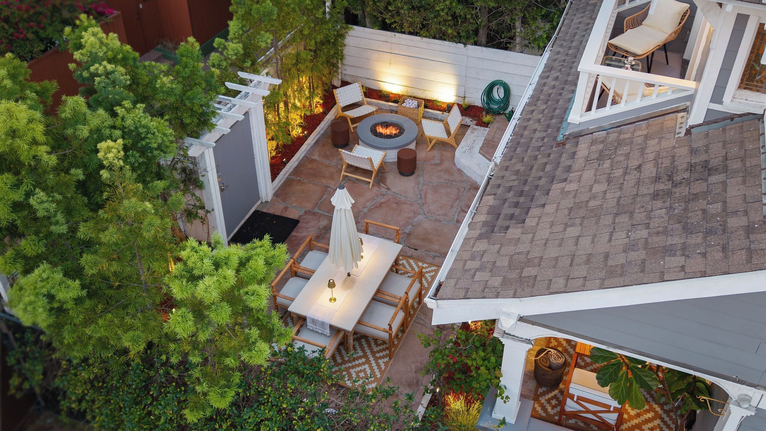 Un patio con un brasero, asientos y un pequeño jardín.
