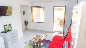 A living room with a red sofa, a glass coffee table, a white cabinet, and a large window. - Appartement Standard a Cayenne Baduel (Cayenne)
