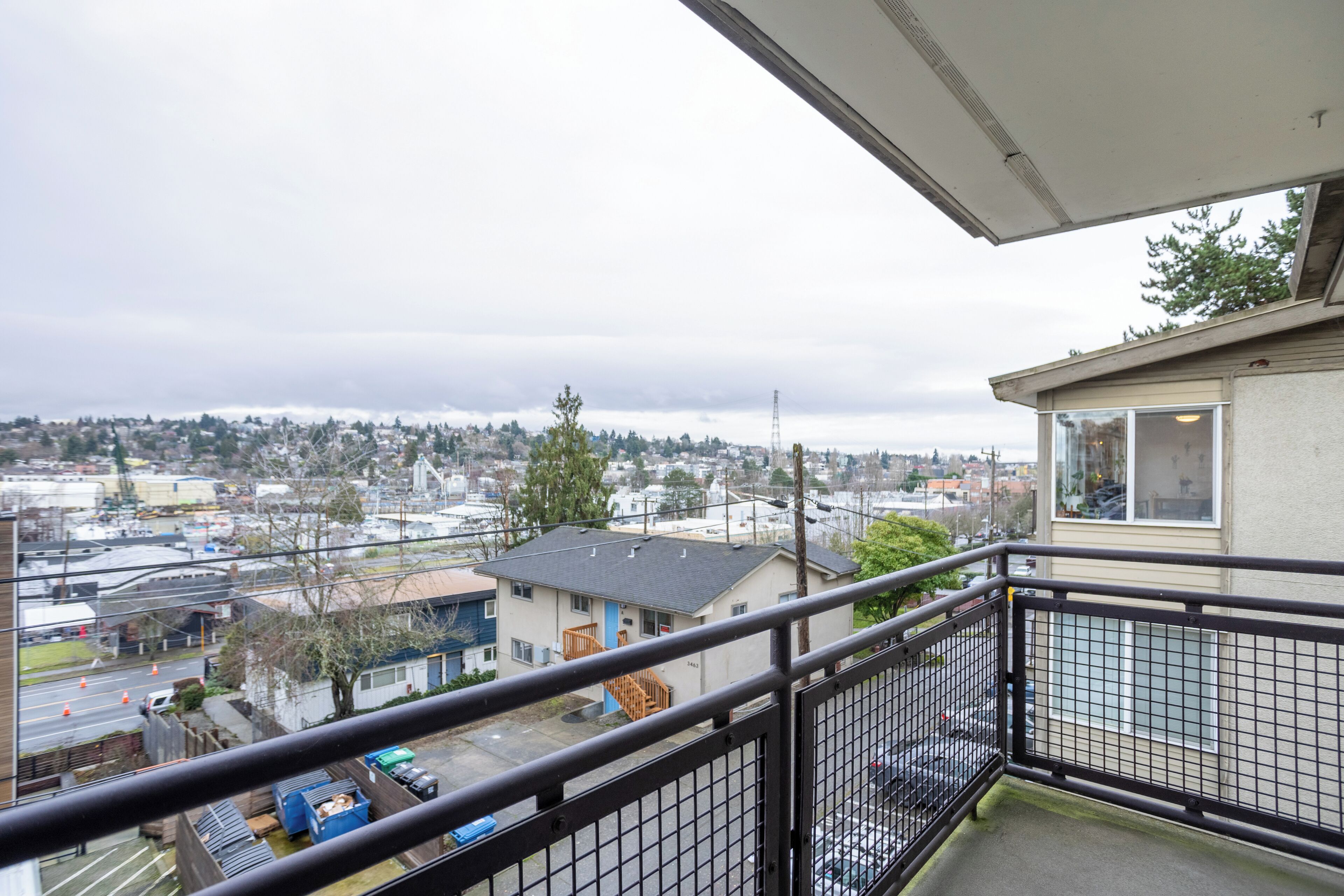 A balcony with a view of a residential area, including houses and a road with traffic cones.