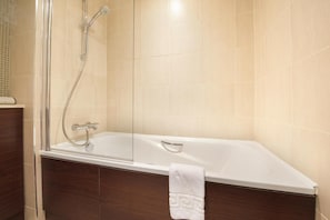 A modern bathroom with a glass-enclosed shower, a white bathtub, and dark wooden cabinetry. - Bicester Country Club (Bicester)