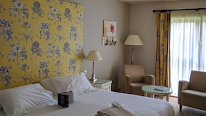 A hotel room with a large bed, two armchairs, a small table, and a nightstand. - Bicester Country Club (Bicester)