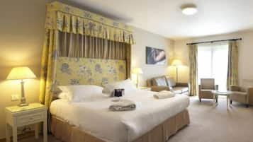 A hotel room with a large bed, two bedside tables with lamps, a chair, a small table, and a window with curtains.