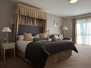 A hotel room with a large bed, two bedside tables, a headboard, and a window with curtains.