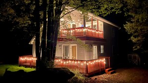 Uma casa de dois andares com varanda e luzes de Natal.