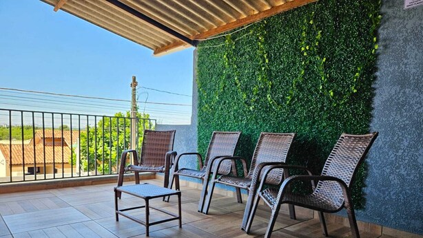 Un balcon avec des fauteuils en osier et un mur végétal.