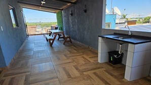 Une pièce spacieuse dotée d’un parquet en bois disposé en chevrons, d’un coin cuisine avec un évier et des placards, et offrant une vue sur l’extérieur.