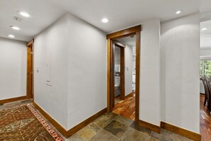 A hallway with white walls, wooden trim, and a patterned rug. - Spacious Vail Golf & Ski Condo, Pool, Hot Tub (Vail)