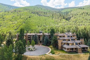 Un hôtel à plusieurs étages doté d’une cour intérieure bordée d’arbres, le tout situé au pied de collines verdoyantes.