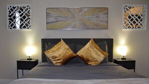 Un dormitorio ordenado con una cama grande, dos mesitas de noche con lámparas y paneles decorativos en la pared.