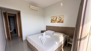 Une chambre d’hôtel avec un grand lit, une table de chevet, un appareil de climatisation et un tableau au mur.