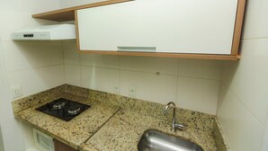 Une petite cuisine avec un plan de travail en granit, une cuisinière à gaz, un évier et un meuble blanc au-dessus du plan de travail.