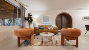 Un salon comprenant un canapé, deux poufs, une table basse et un tapis.