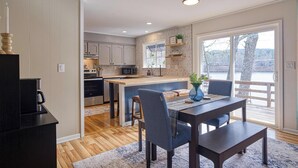 A modern kitchen with a central island, wooden flooring, and a dining area with a table and chairs. - 05202 - 3 Guadalajara Lane (Hot Springs Village)