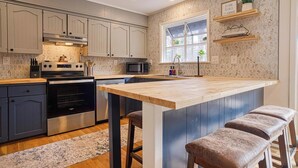 A modern kitchen with grey cabinets, a central island, a microwave, and a stove. - 05202 - 3 Guadalajara Lane (Hot Springs Village)