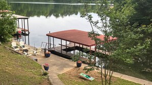 A lakeside deck with chairs, a covered area, and a small boat. - 05202 - 3 Guadalajara Lane (Hot Springs Village)