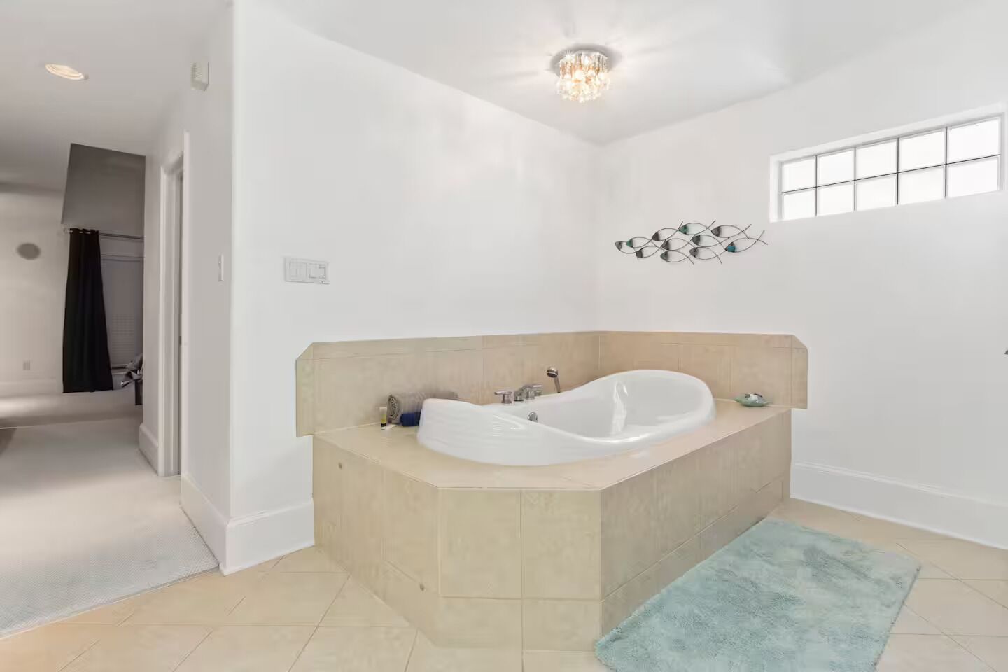 A modern bathroom with a freestanding bathtub, a small window, and a decorative wall piece.