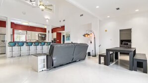 Een moderne woonkamer met een bank, een eettafel en een keuken op de achtergrond.