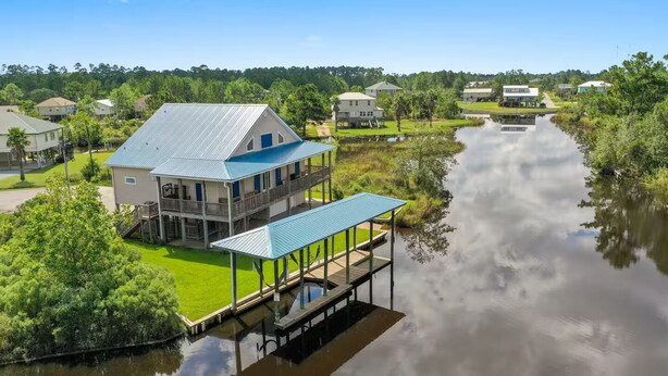 Een pand aan het water met een groot huis, een overdekt terras en een steiger die uitloopt in een rustige rivier.