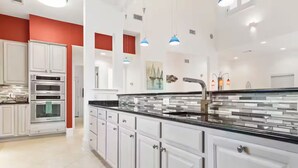 Een moderne keuken met witte kasten, een zwart aanrecht en roestvrijstalen apparatuur.