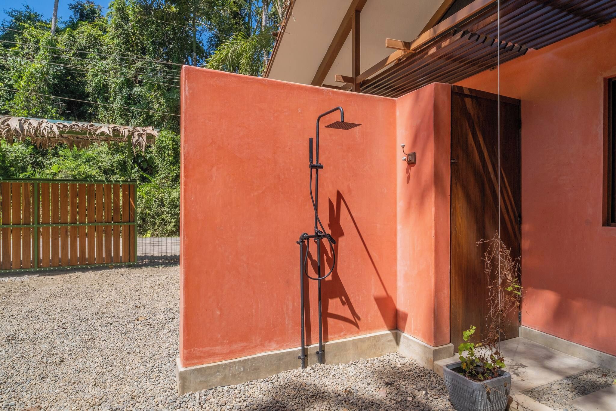 A red wall with a metal structure, possibly a shower, and a wooden door.