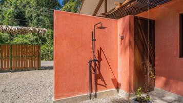 A red wall with a metal structure, possibly a shower, and a wooden door.