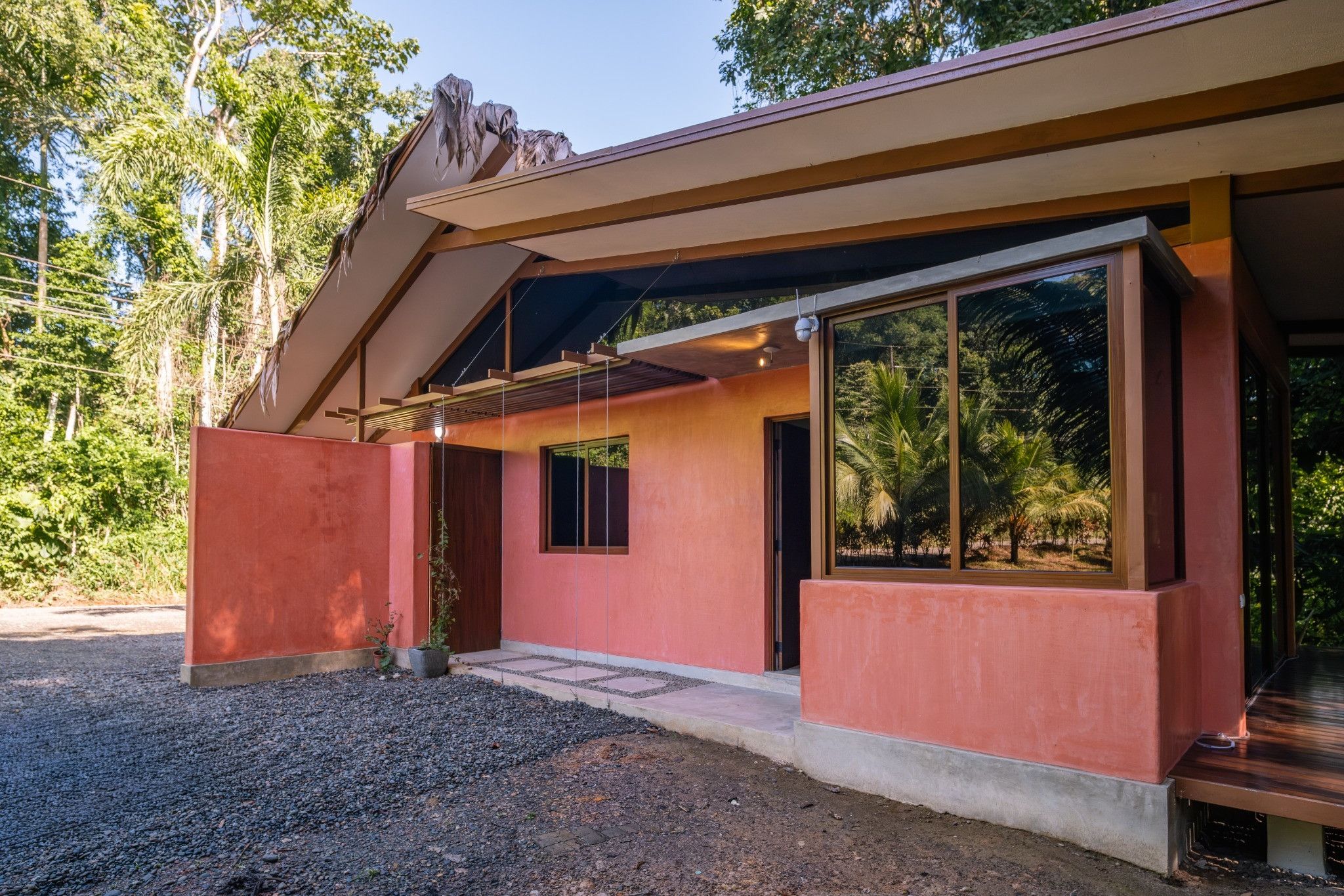 A modern building with a sloped roof, large windows, and a gravel driveway.