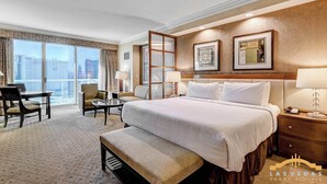 A hotel room with a large bed, a desk, a chair, a sofa, and a view of the city. - MGM Signature- Stripview Balcony F1 Track  Jacuzzi (Las Vegas)