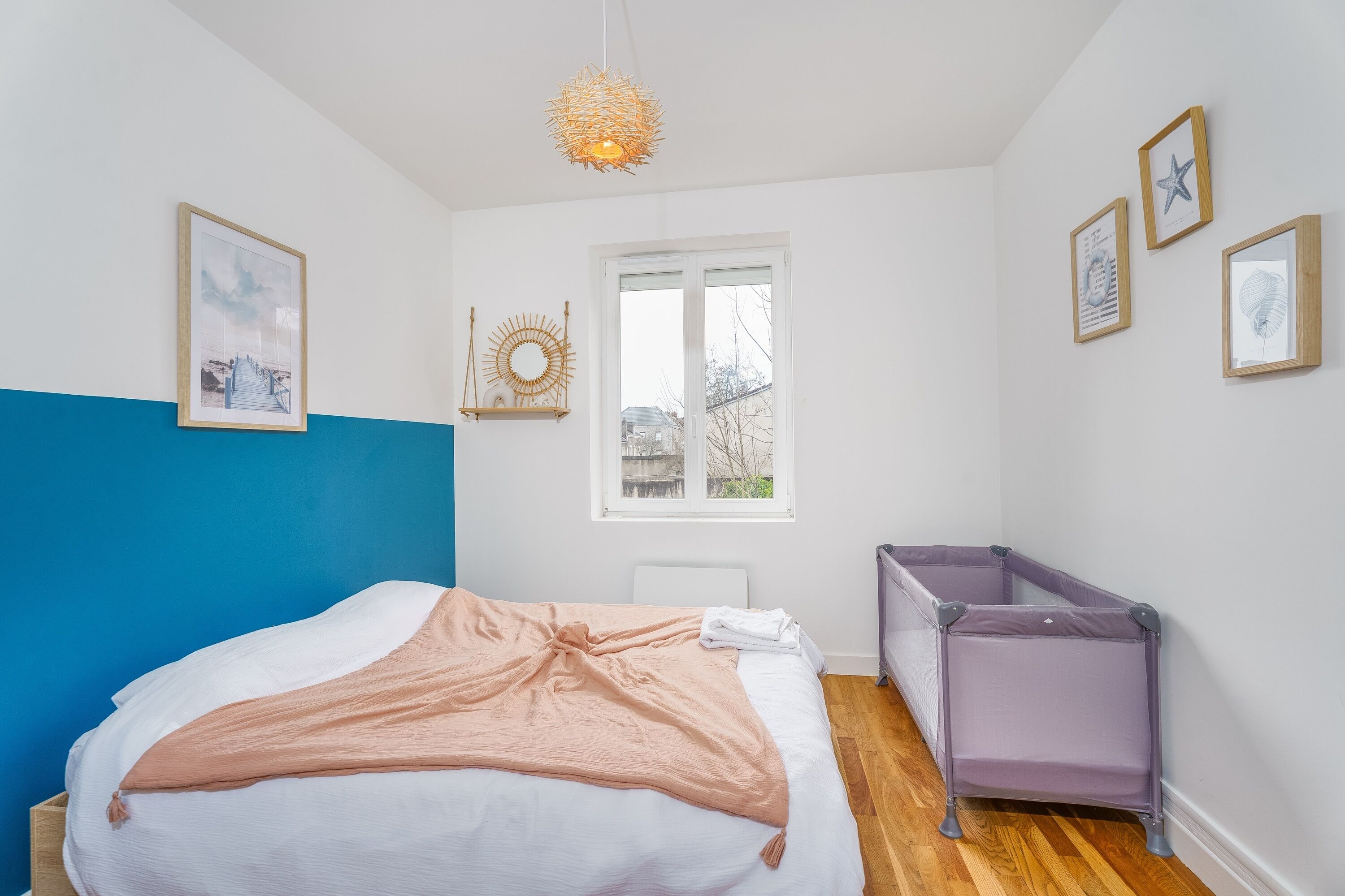 Ein Schlafzimmer mit Bett, Babybett, Fenster und Wanddekorationen.